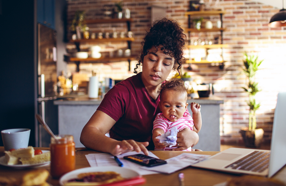 Woman holding baby and working on calculator