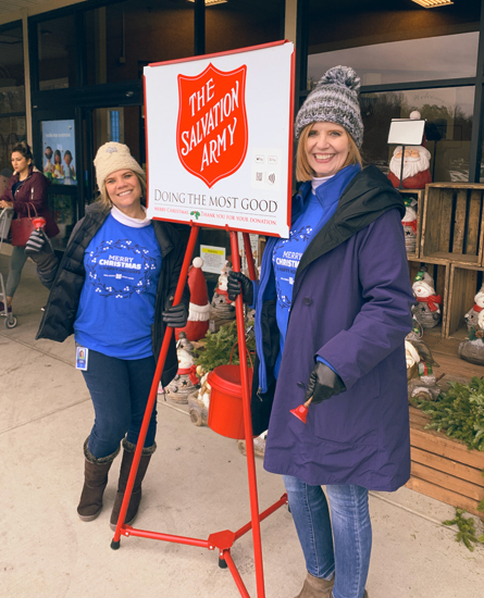 Two women standing next to Salvation Army donate stand